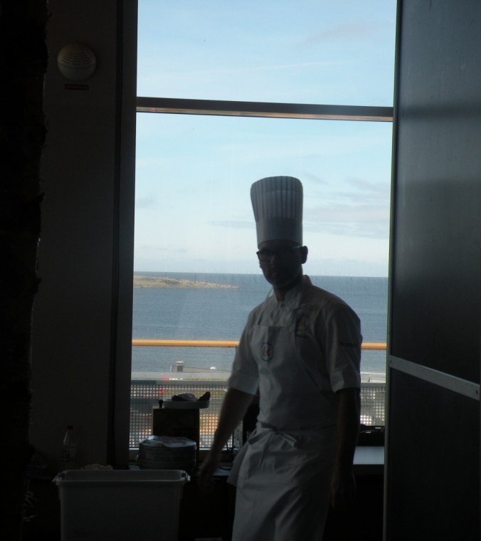 Kock i motljus med havet som kuliss